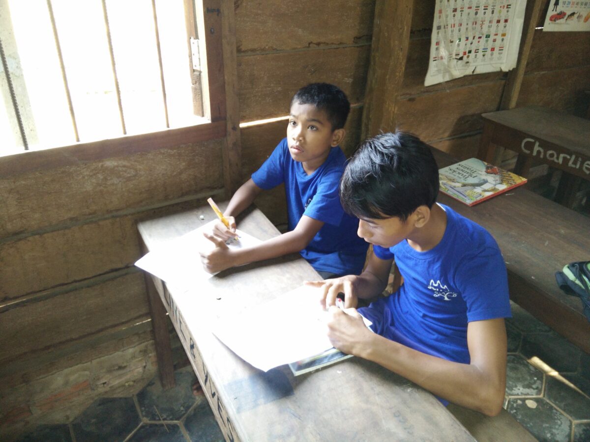 A simple wooden barrack, a class in a Cambodian community school