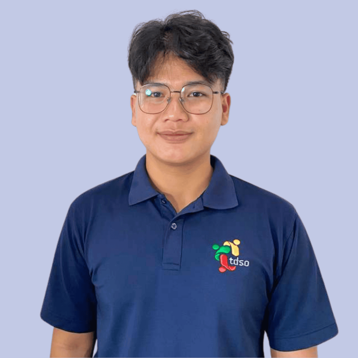 TDSO Young teacher wearing TDSO organisation polo shirt, standing confidently with arms crossed.